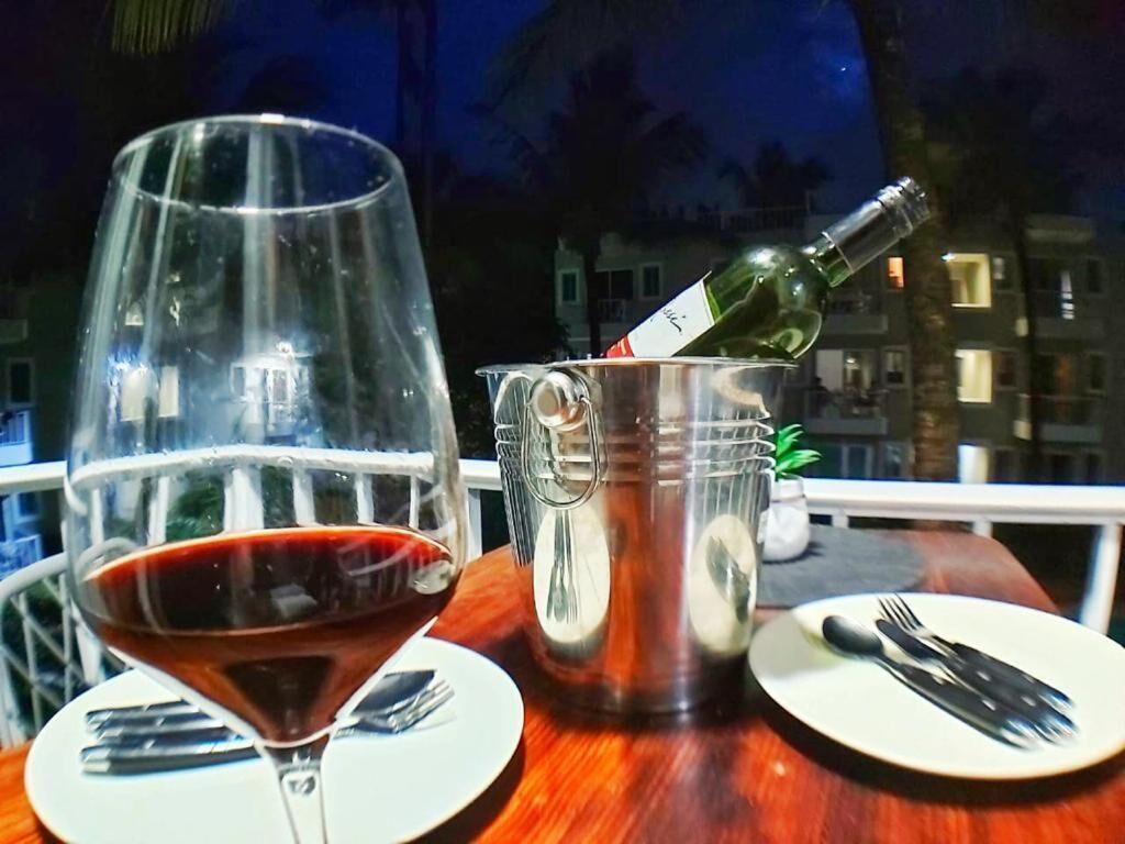 Une table avec un verre à vin et une bouteille de vin dans un récipient en métal, ainsi que des assiettes et des couverts sur la table.