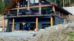 Un chalet moderne à deux étages, doté d’un grand balcon, de poutres en bois et de fondations en pierre.