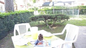 A table set outdoors with chairs, a pine cone, sunglasses, and a magazine. - Lovely Villa Just 500mt From the sea (San Michele al Tagliamento)