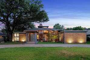 Une maison moderne avec une façade en briques, de grandes fenêtres et une pelouse bien entretenue.