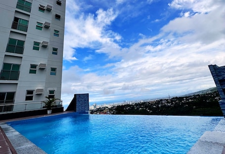 Una piscina al aire libre, sombrillas, sillones reclinables de piscina