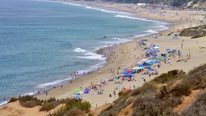 Una playa con gente, sombrillas y una torre de salvavidas.