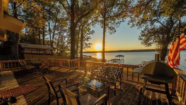 A wooden deck with outdoor furniture, a grill, and an American flag. - Welcome to Catfish Cabin! (Henderson)