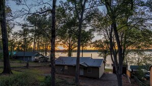 A cabin with a small porch and a view of a lake at sunset. - Welcome to Catfish Cabin! (Henderson)