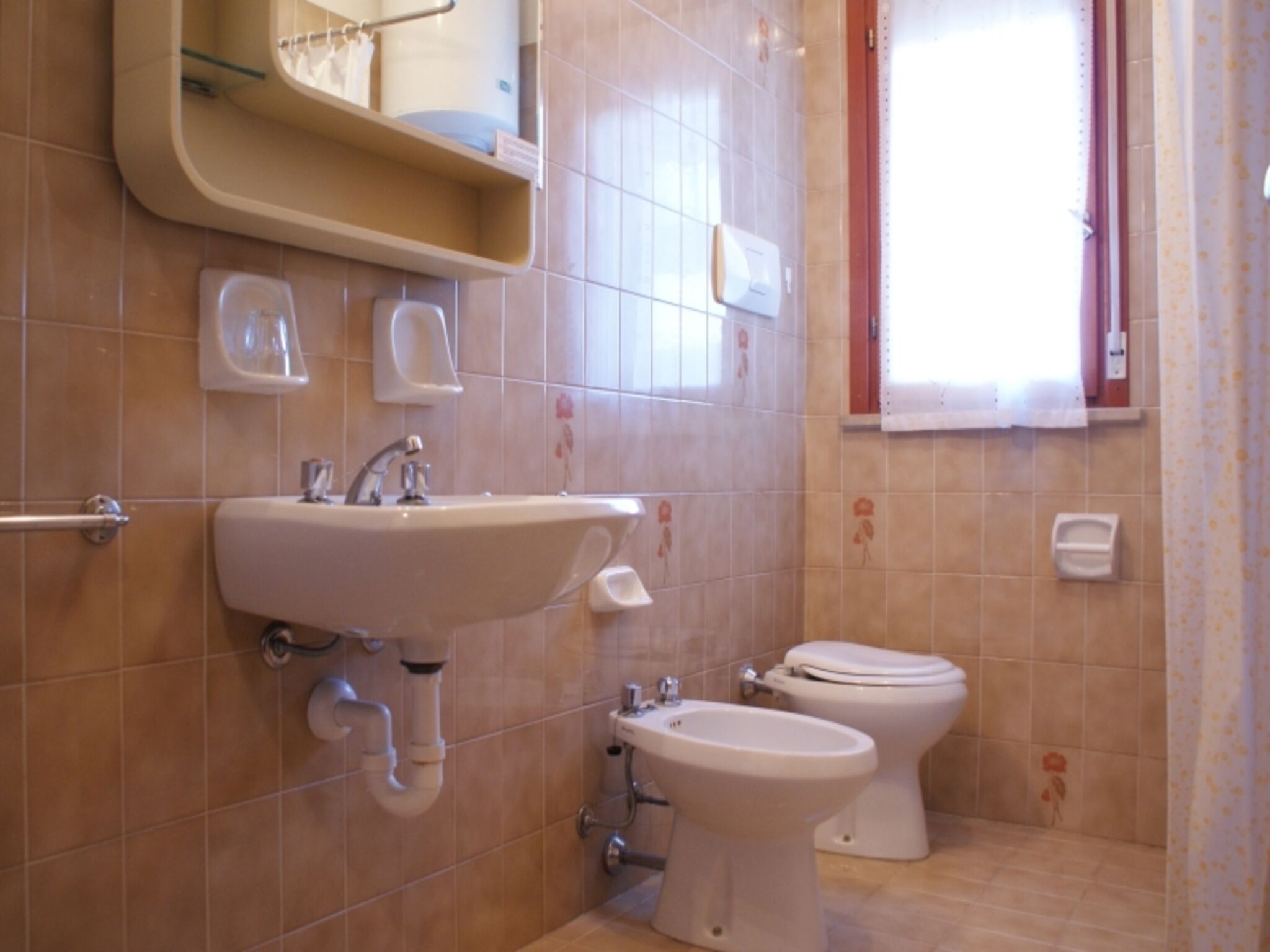 A bathroom with a sink, bidet, and toilet.