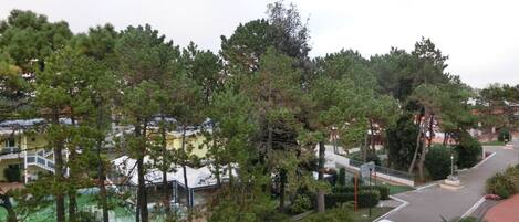 A residential area with a road, green spaces, and a building with a balcony.