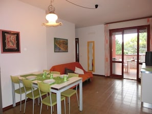 Un comedor con una mesa preparada para cuatro personas, un sofá y un cuadro abstracto grande en la pared.
