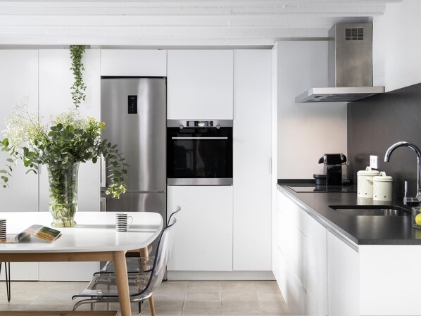 Een moderne keuken met een roestvrijstalen koelkast, oven en een inbouwafzuigkap.