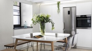 A modern kitchen with white cabinets, a stainless steel refrigerator, and a built-in oven.