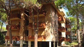 A multi-story building with balconies, surrounded by trees.
