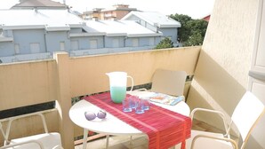 A small outdoor patio with a round table, white chairs, a red tablecloth, and a pitcher. - Nice Flat With Terrace-beahost (San Michele al Tagliamento)