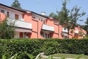 Fileira de edifícios rosa e brancos com uma sebe bem cuidada em primeiro plano.
