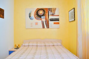 Une chambre à coucher avec un lit, un tableau accroché au mur et une table de chevet avec une lampe.