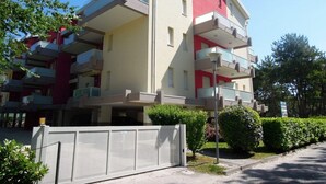 A multi-story residential building with balconies, a gated entrance, and a clear sky. - Flat 100 m From the Beach With Sunny Balcony (San Michele al Tagliamento)