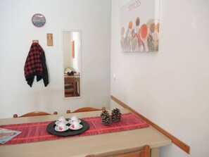 A dining area with a table set for four, a clock, a mirror, and a wall art piece titled 'SPICES'. - Flat 100 m From the Beach With Sunny Balcony (San Michele al Tagliamento)