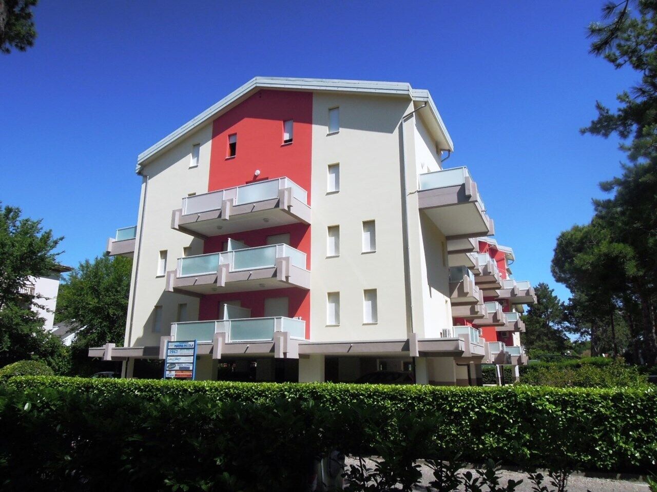 A multi-story building with balconies, a signboard, and a clear blue sky.