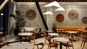 A modern restaurant with round tables, a sofa, and decorative wall art. - Horizon by SkyCity  (Auckland)