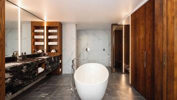 A modern bathroom with a freestanding bathtub, marble-tiled floor, wooden vanity, and a large mirror.