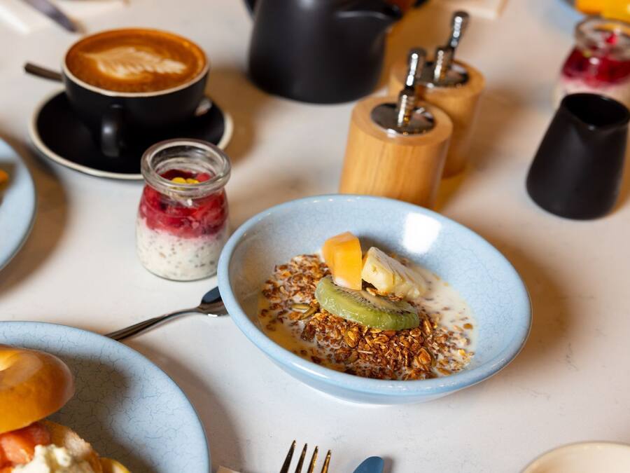 Une table dressée pour le petit-déjeuner avec des croissants, des œufs brouillés et un bol de céréales aux fruits.