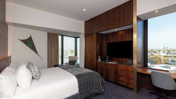 Ein modernes Hotelzimmer mit einem großen Bett, einem Schreibtisch und einem Flachbildfernseher, mit Blick auf die Stadt.