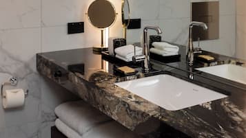 A modern bathroom with two sinks, a round mirror, and a towel rack.