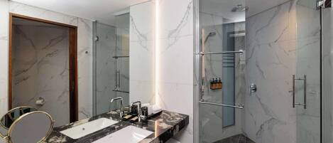 A modern bathroom with a dual sink vanity, a glass shower enclosure, and a marble-tiled shower area.