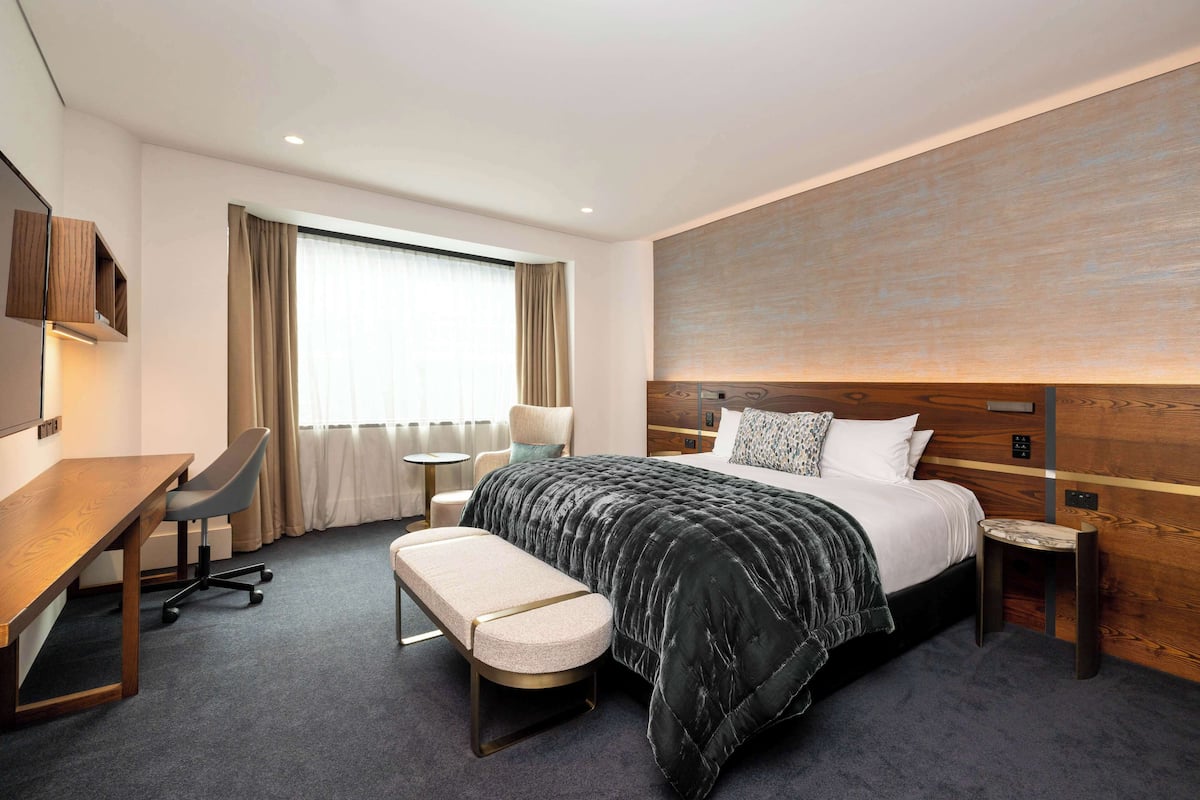 Une chambre d’hôtel avec un lit, un bureau, une chaise et une petite table.