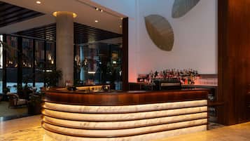 Eine moderne Bar mit einer gebogenen Marmor-Bar, einer großen Säule und Blick auf die Stadt durch große Fenster.