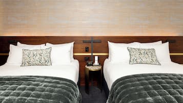 Een hotelkamer met twee bedden, een nachtkastje en een wandklok.