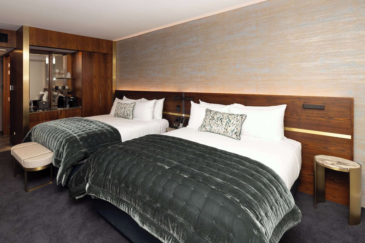 Une chambre d’hôtel avec deux lits, un coin salon, un miroir et une petite table.