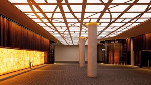 A spacious lobby with a modern design, featuring a patterned ceiling, large columns, and a warm light source on the left. - Horizon by SkyCity  (Auckland)
