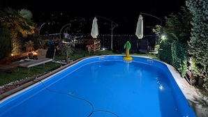 A swimming pool with a small inflatable toy, surrounded by outdoor furniture and plants. - Villa Georgina With Cats (Opatija)