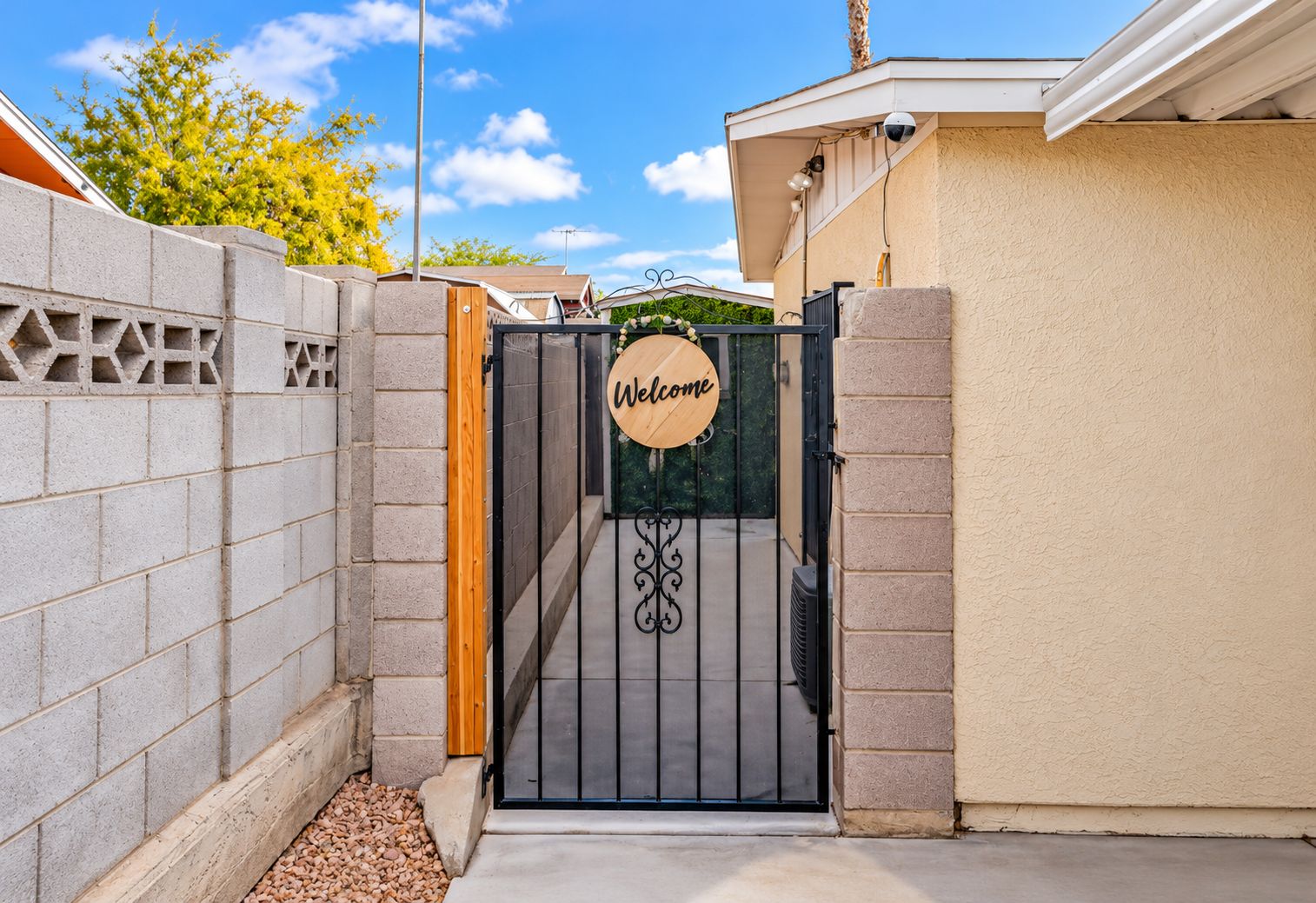 A gated entrance with a 'Welcome' sign, a metal gate, and a concrete wall.