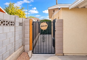 A gated entrance with a 'Welcome' sign, a metal gate, and a concrete wall. - Private Studio in Las Vegas with Two Beds, Kitchenette & Parking (Las Vegas)