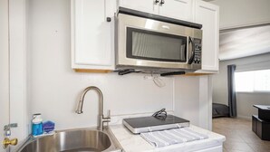 A compact kitchenette with a stainless steel sink, a microwave, and a small countertop.