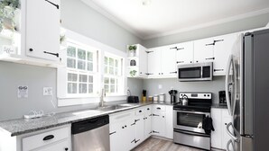 A modern kitchen with white cabinets, stainless steel appliances, and a granite countertop.
