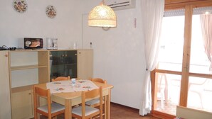 A compact kitchen with a dining table, chairs, and a hanging light fixture. - Warm Two-room Flat With Balcony Near the Beach (San Michele al Tagliamento)