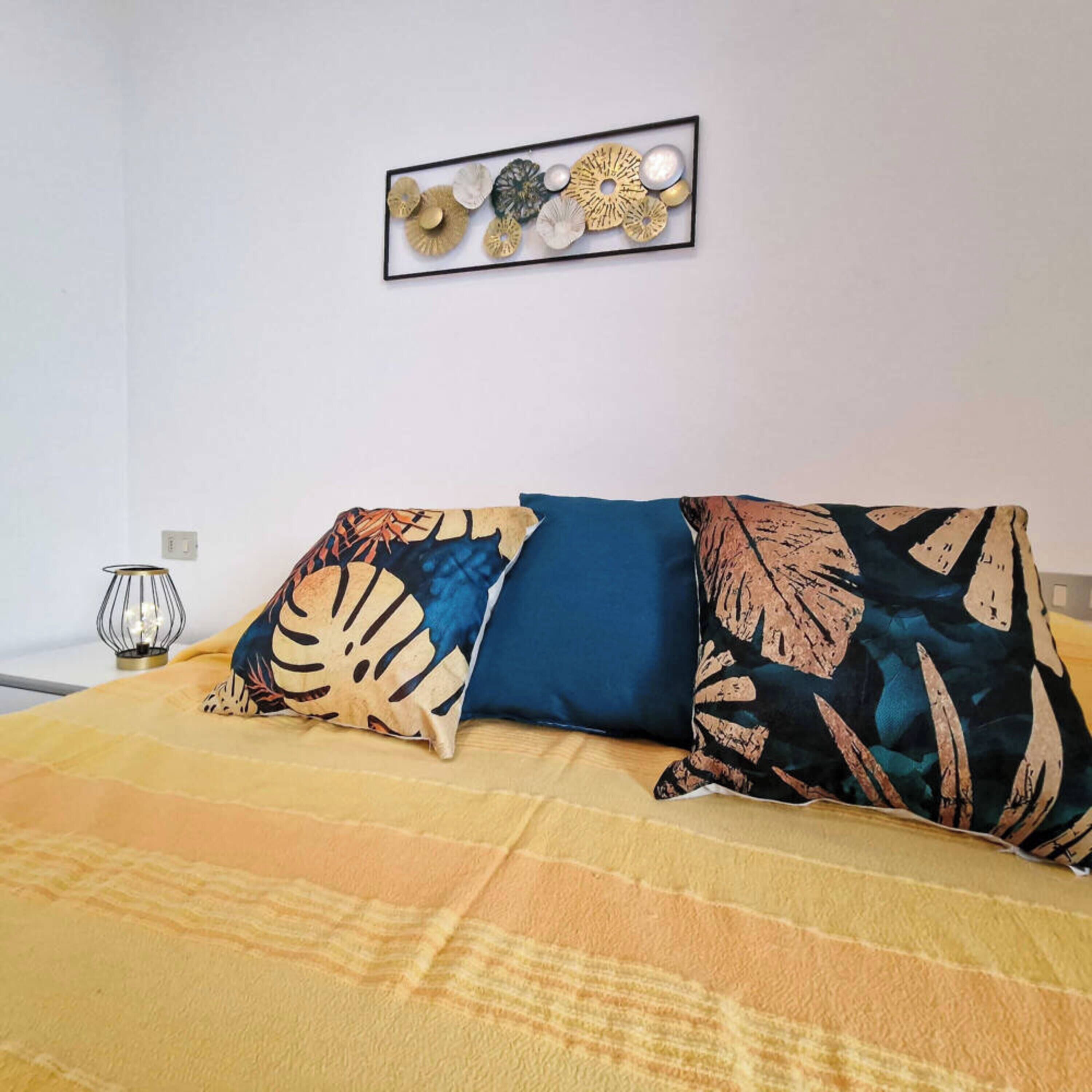 A bed with patterned pillows and a wall-mounted decorative piece.
