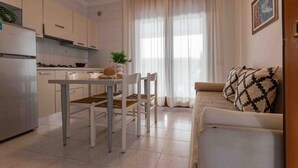 Eine moderne Küche mit weißen Schränken, einem Esstisch mit Stühlen und einem Sofa im Wohnbereich.