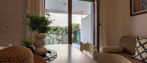 A modern living room with a sofa, a round woven table, and a potted plant.