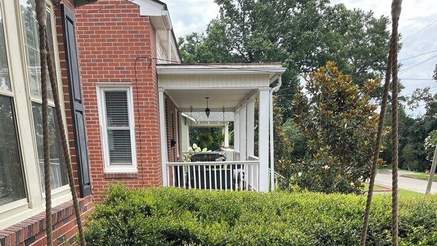 A wooden bench with patterned cushions on a brick patio. - Masters rental - Designer MCM updated bungalow   (Augusta)