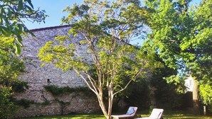 A stone wall with a tree in front of a building. There are two lounge chairs in the grass. - 4 Bed Villa - Sleeps 8 - Garden - Fireplace (Port-Sainte-Foy-et-Ponchapt)