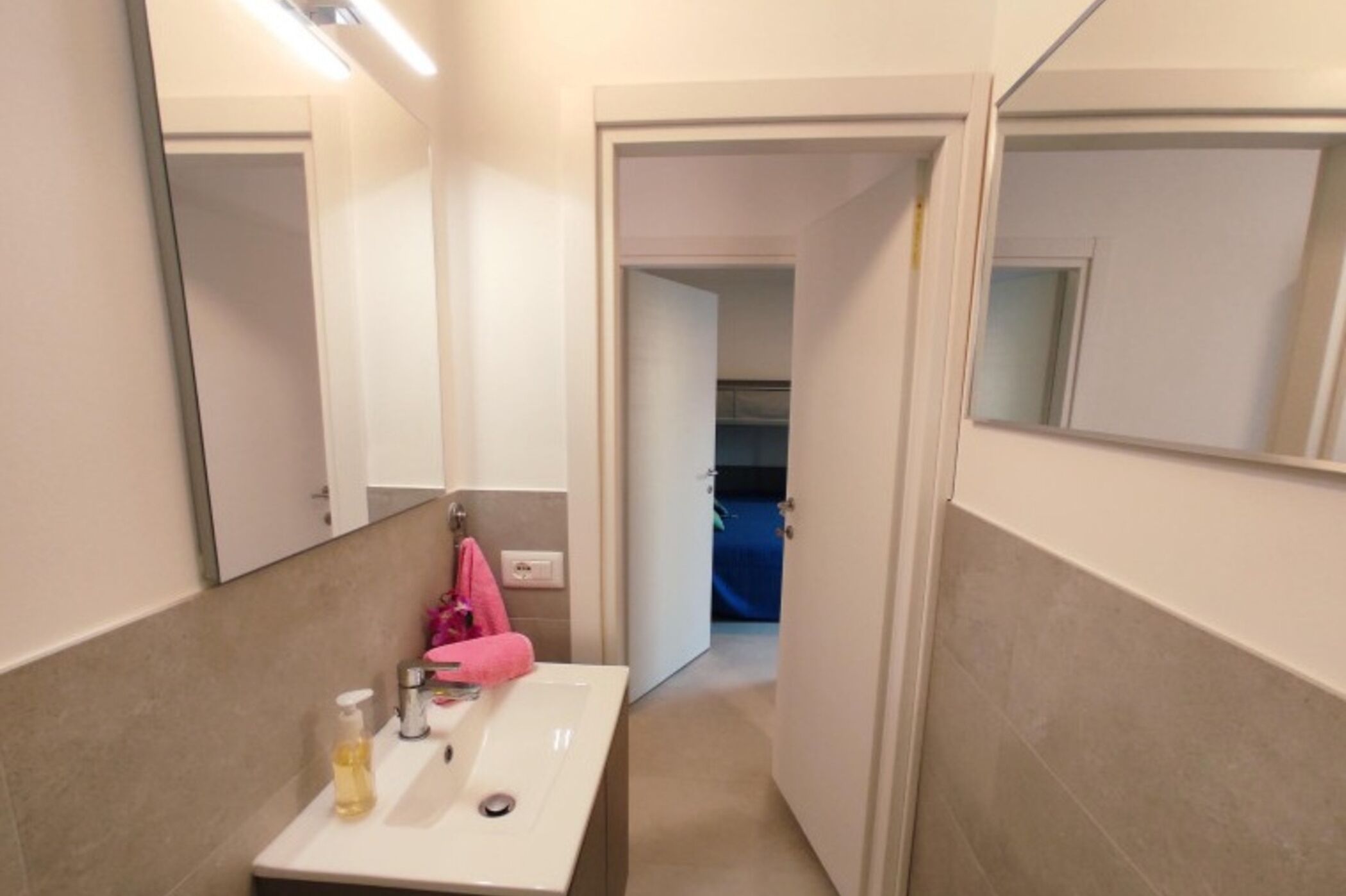 Une petite salle de bain avec un lavabo blanc, un miroir et un porte-serviettes.