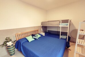 A bedroom with a bunk bed, a bedside table, a lamp, and a small round table.