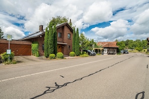 A two-story brick house with a garage, a covered porch, and a car parked in front.