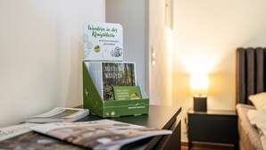 En brochureholder med en bog med titlen 'Wander in der Königsklasse' og en lampe på et natbord.
