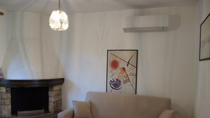 Un salon avec une cheminée en pierre, un canapé beige, une table basse en bois et un tableau abstrait encadré accroché au mur.