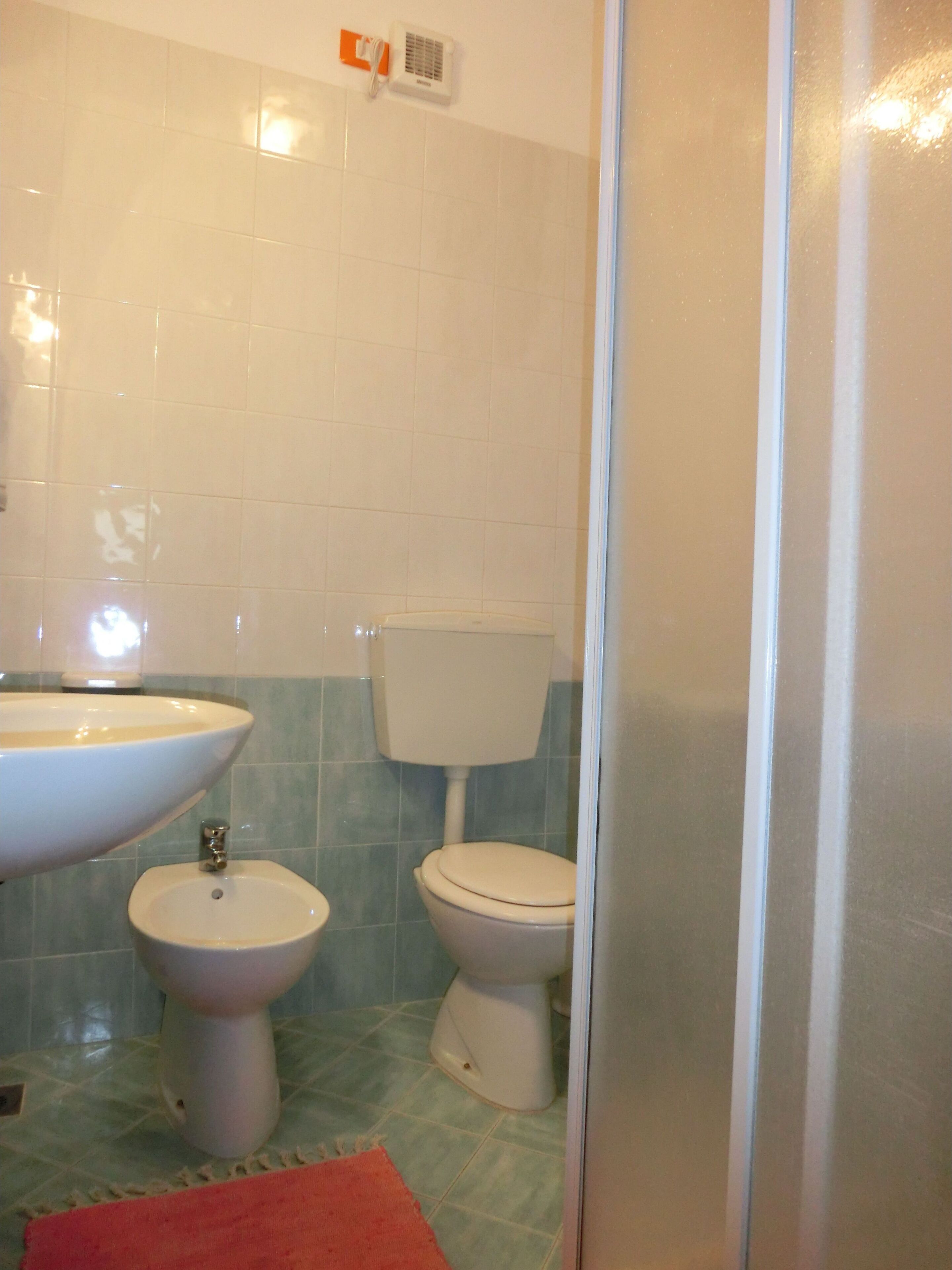 A bathroom with a sink, bidet, toilet, and a shower area.