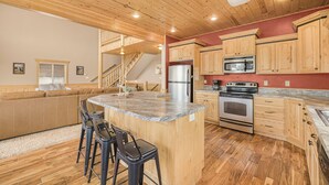 A spacious kitchen with wooden cabinets, a granite countertop, a built-in oven, and a stainless steel refrigerator. - Elk Ridge Retreat-25m to Yellowstone+hot tub+home theater (island park)