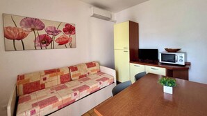 A kitchenette with a microwave, a small refrigerator, and a wooden table with a plant. - Relaxing Villa With Private Garden Near the sea (San Michele al Tagliamento)